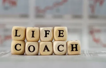 Stacks of wooden letter cubes spelling 'LIFE' over 'COACH'.
