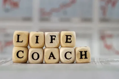 Stacks of wooden letter cubes spelling 'LIFE' over 'COACH'.